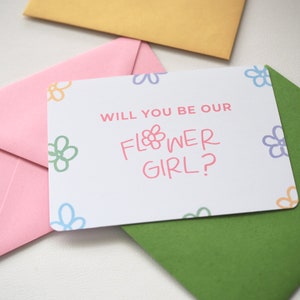 Pink flower girl proposal greeting card with question text and floral corner accents