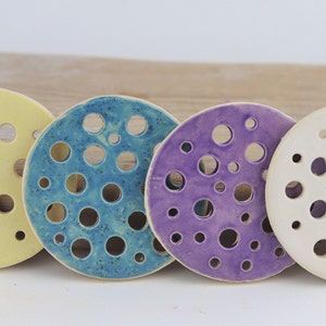 Set of ceramic flower frogs in blue, purple, yellow, and cream with pinhole openings