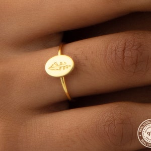 Gold-tone dainty ring with oval birth-flower charm on finger