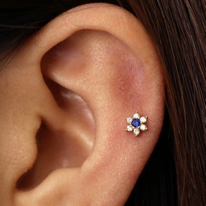 Sapphire flower labret stud earring with blue center gem on ear cartilage