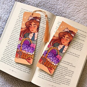 Flower-themed illustrated bookmark with cartoon girl, orange top clip and hanging ribbon