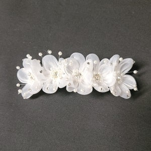 White floral hair barrette with pearl bead accents and clear ribbon loops