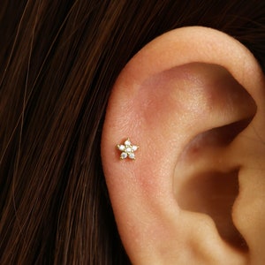 Gold flower cartilage stud earrings with small diamond-like center