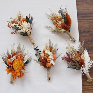 Floral boutonniere with burnt orange blooms and eucalyptus leaves, wrapped in twine.