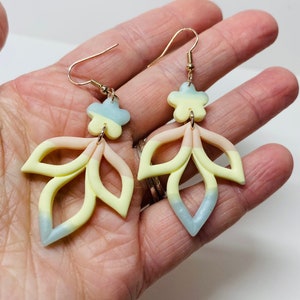 Handmade polymer clay floral dangle earrings in pastel blue, yellow, and pink with rose-gold hooks