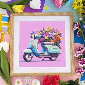 Framed cross-stitch pattern artwork of a floral Vespa scooter with bouquet