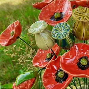 Ceramic poppy flower decoration: red petals, green buds, black centers, on stems.