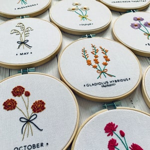 Embroidery hoop art kit with floral month designs, including October and May