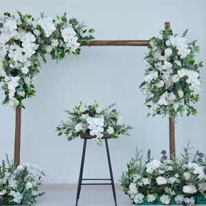 White floral wedding arch arrangement with greenery, orchids and peonies on a wooden frame