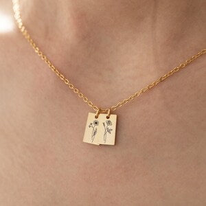 Gold-tone necklace with small square pendant charm and birth-flower style engraving