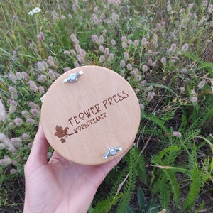 Round wooden flower press with metal corner clips, botanical herbarium tool