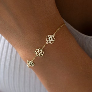 Gold-tone bracelet with small flower charms on wrist, delicate chain