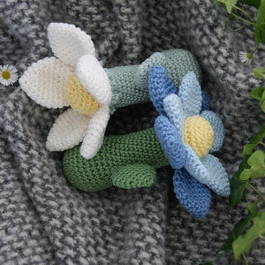 Crochet flower rattle pair with white/yellow and blue/green petals and plush fabric body