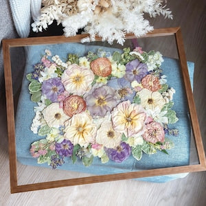 Framed preserved flower bouquet with pastel blooms in a wooden shadowbox frame