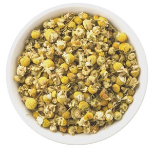 Organic chamomile flower tea, dried loose flowers in a white bowl