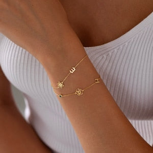 Gold-tone charm bracelet with small flower and star letter-style charms