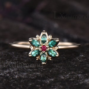 Delicate flower halo ring with pink center ruby and emerald green stones on thin band