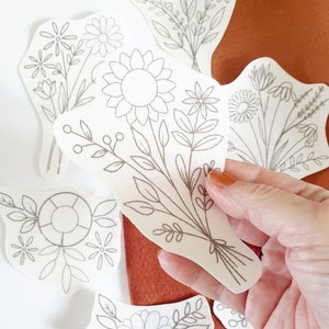 Washaway embroidery stabilizer sheet with floral line patterns, held in hand