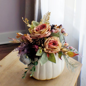 Fall silk flower arrangement in white pumpkin-shaped planter with roses and greenery