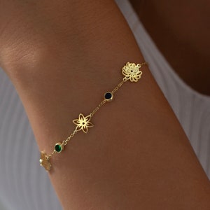 Gold-tone birth flower bracelet with small flower charms and green birthstone beads