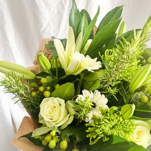 Fresh flower lily bouquet with white lilies, light roses, and green foliage, wrapped
