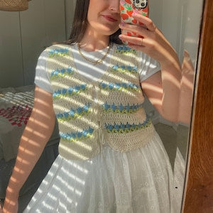 Cream crochet vest with blue and yellow stripe pattern, sleeveless, floral details