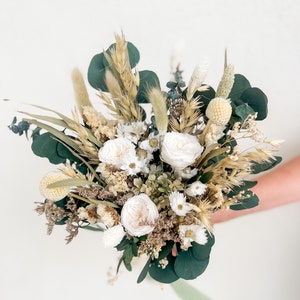 Dried floral bouquet with white blooms, green leaves, and pampas grass stems