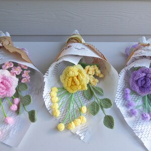 Crochet flowers bouquet with yellow blossoms and green leaves in white paper wrap