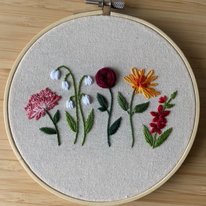Embroidered flower hoop decoration with colorful blooms on light gray fabric