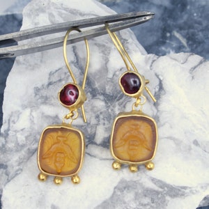Gold bee intaglio glass drop earrings with garnet accents