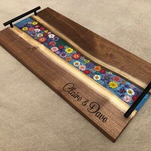 Wooden charcuterie serving board with floral inlay and metal handle accents