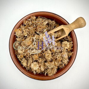 Dried arnica flowers in a ceramic bowl with wooden scoop