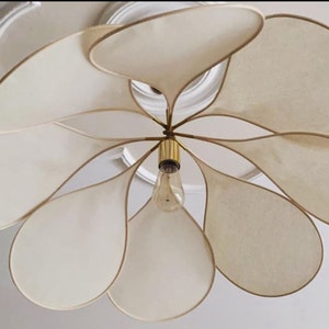 Petal pendant lamp with cream fabric petals and central metal stem over glass socket