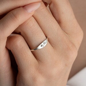 Dainty silver-toned ring with engraved flower design and lettering band