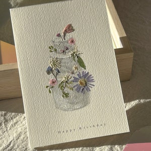 Pressed flower birthday card with blue and pink floral bouquet and "Happy Birthday" text