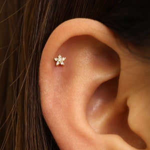 Tiny gold flower cartilage labret stud earring on ear