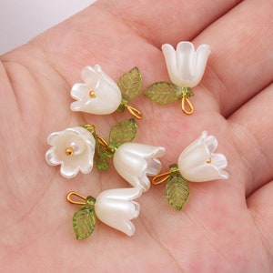 10 white lily-of-the-valley bell charm pendants with green leaf details, pearl-like finish