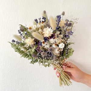 Dried flower wedding bouquet with white and blue blooms, greenery, and thistles