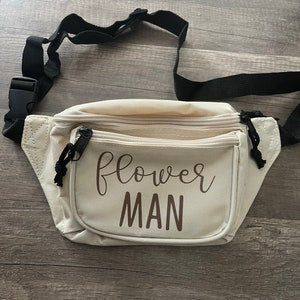 Cream fanny pack with black zipper pocket and “Flower MAN” front print.