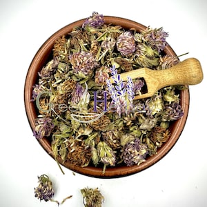 Loose dried red clover herbal tea flowers in a wooden bowl with scoop