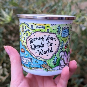 Enamel mug with colorful illustration and text "Journey from womb to world"
