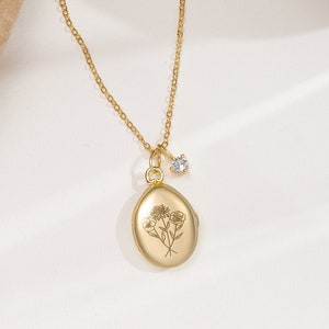Gold birth-flower locket necklace with round engraved tree pendant and clear stone bail