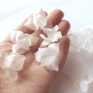 3D white fabric flower petal embellishments in hand for wedding headpieces