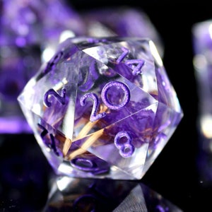 Purple translucent polyhedral dice with engraved numerals and decorative swirls