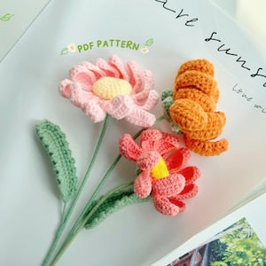 Crochet flower pattern with pastel pink and orange crocheted blooms on paper