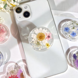 Transparent floral phone grip with pressed dried flowers in a round disc