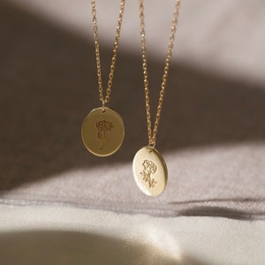 Tiny round birth flower necklace with two small floral pendants on thin gold chain