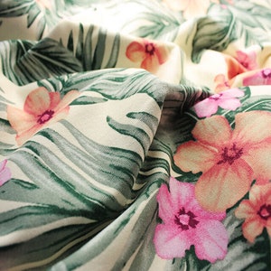Cotton fabric with tropical palm leaves and pink frangipani flowers, folded