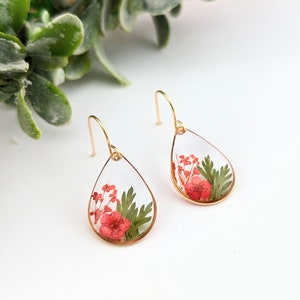 Teardrop resin flower earrings with red pressed blooms and green leaves, gold hook backs