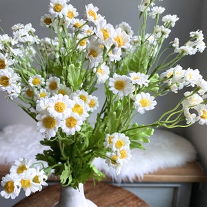 Artificial chamomile flower spray with white petals and yellow centers, green stems and leaves